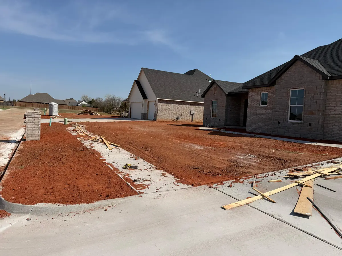 Fresh red dirt final grade across front yards of two new brick homes