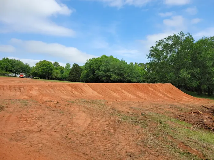 Long sculpted red dirt berm edging a freshly graded pad