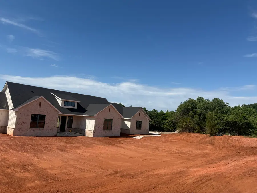 Finished grade around a new white brick farmhouse