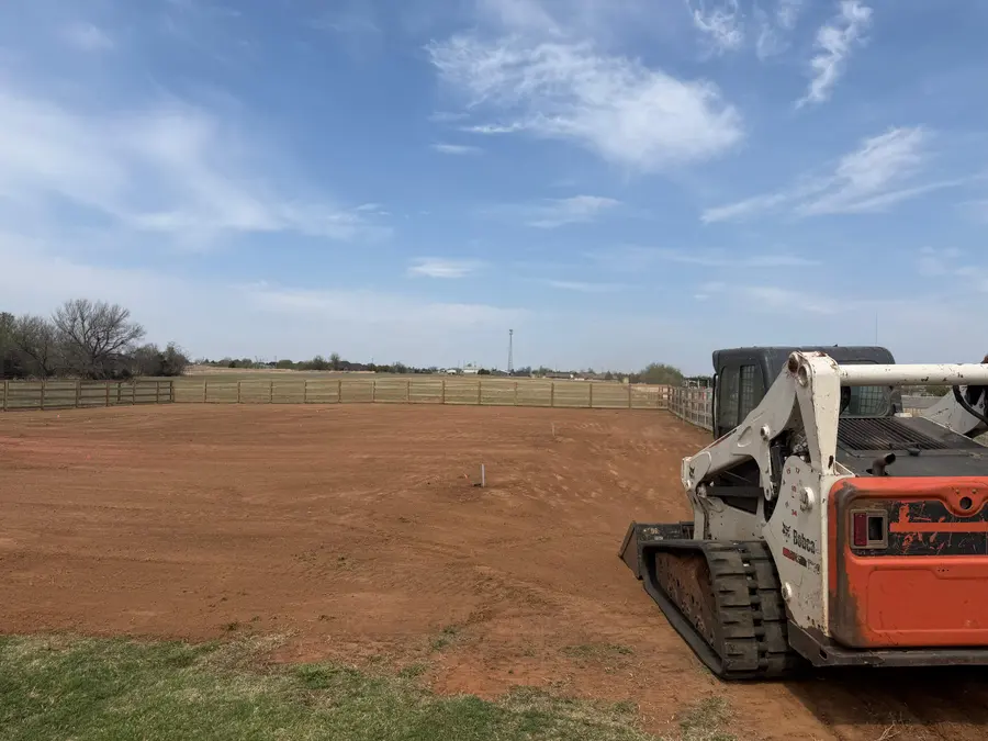 Skid steer on a finished fenced arena pad