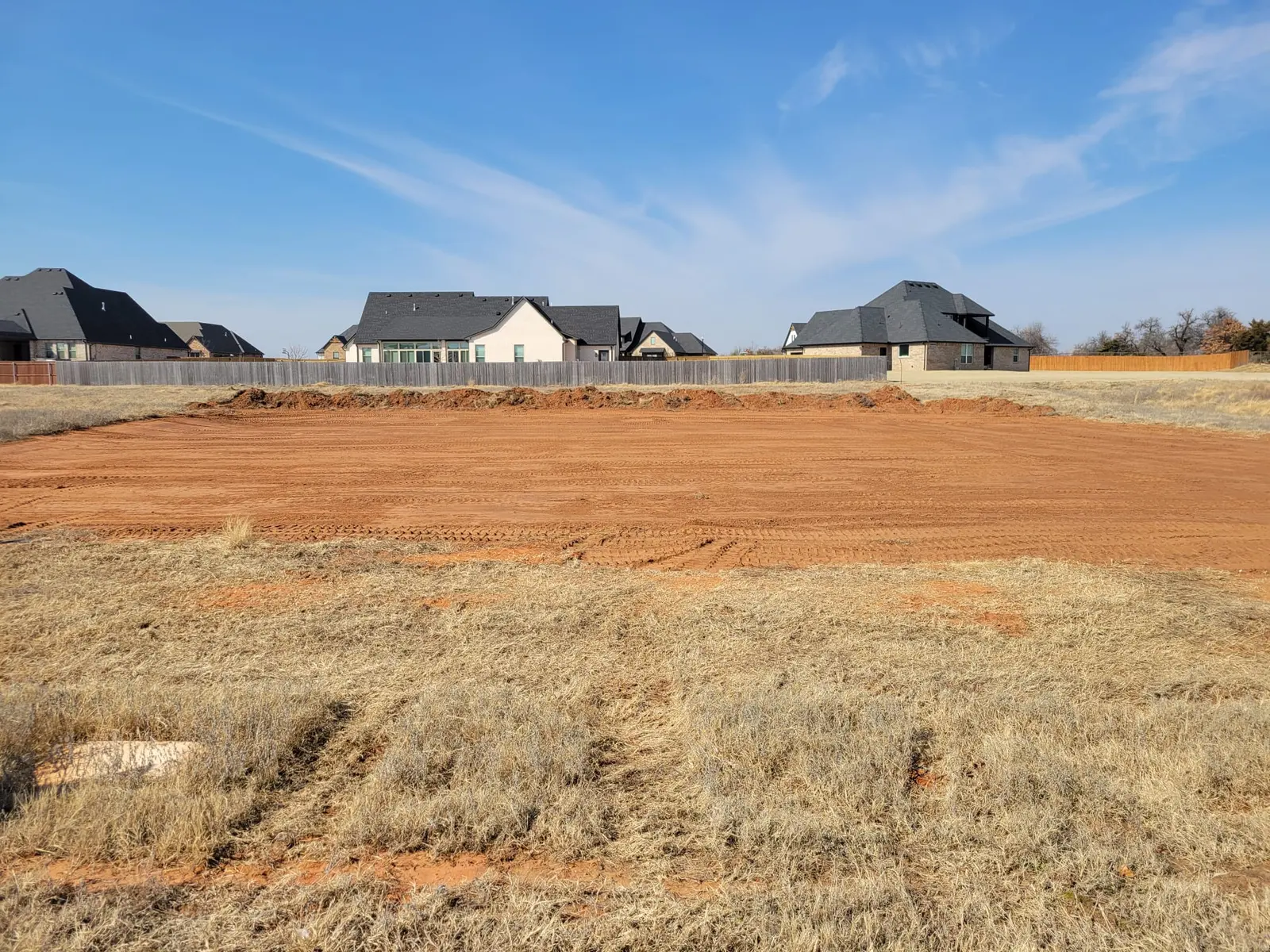 Clean leveled building pad with perimeter berm and grade stakes set